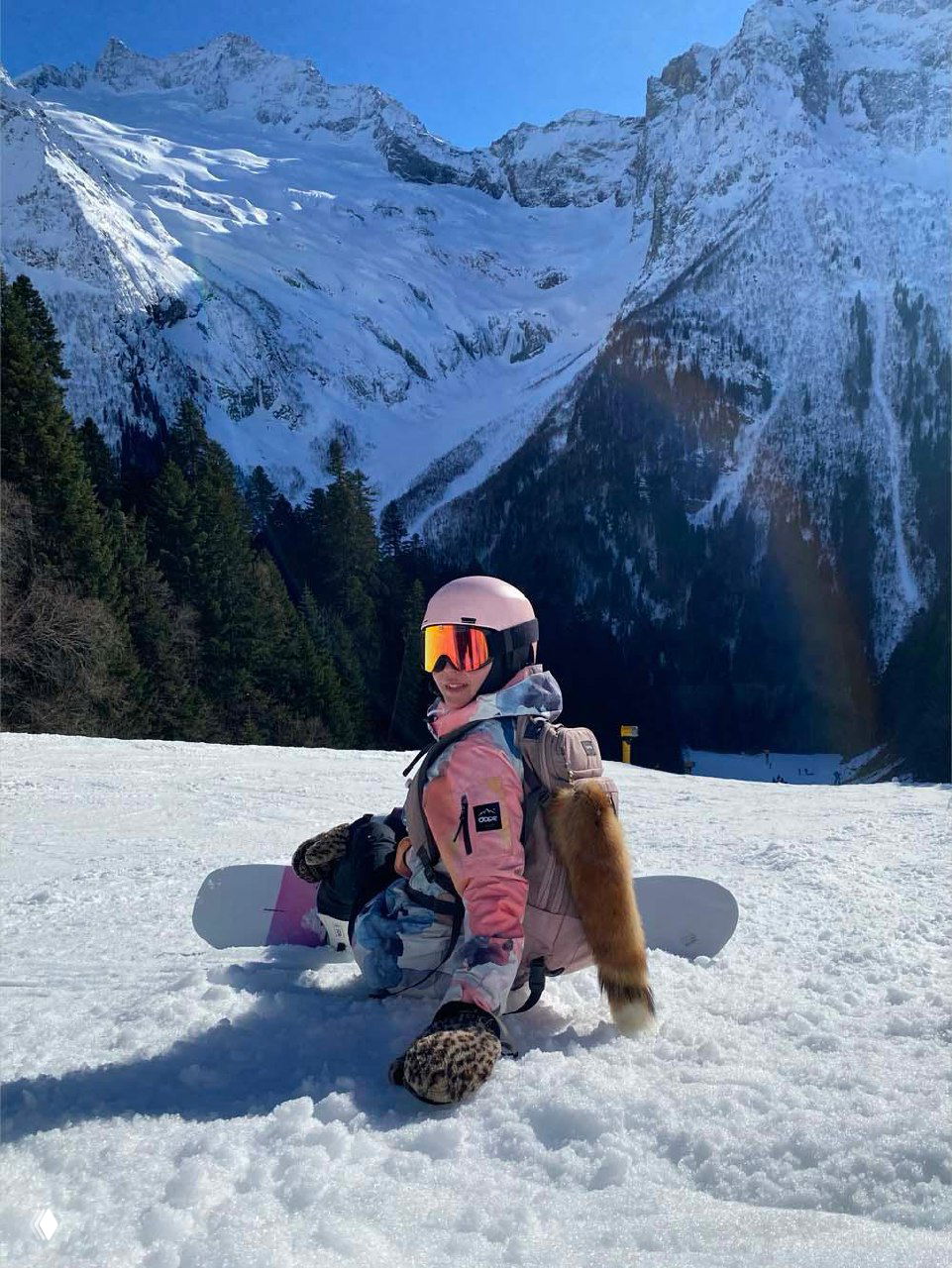 Падение или отдых на снегу: лыжник лежит на заснеженном склоне на фоне высоких гор, сцена передаёт динамику и природные пейзажи зимнего Кавказа.