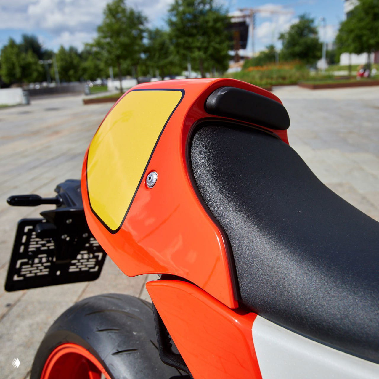 Деталь задней части Yamaha XSR900 GP: одиночное сиденье и красно‑жёлтая облицовка хвоста, видна задняя часть кронштейна номера и покрышка.