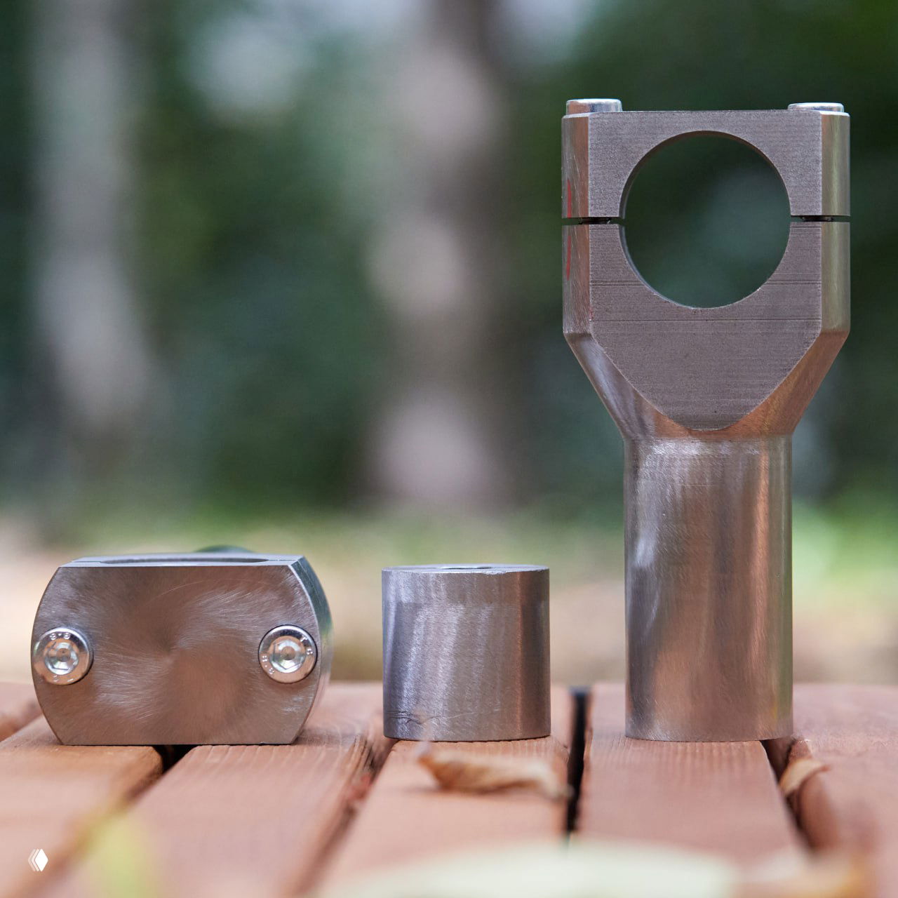 Металлические составные стойки и проставка для руля, три фрагмента на деревянной поверхности, крупный план деталей для установки руля.