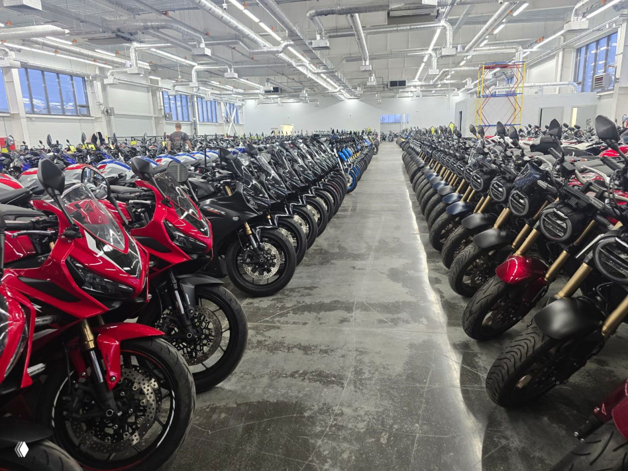 Панорамный вид внутреннего зала большого мотосалона в Мытищах: плотно расставленные ряды новых мотоциклов разных марок и классов.