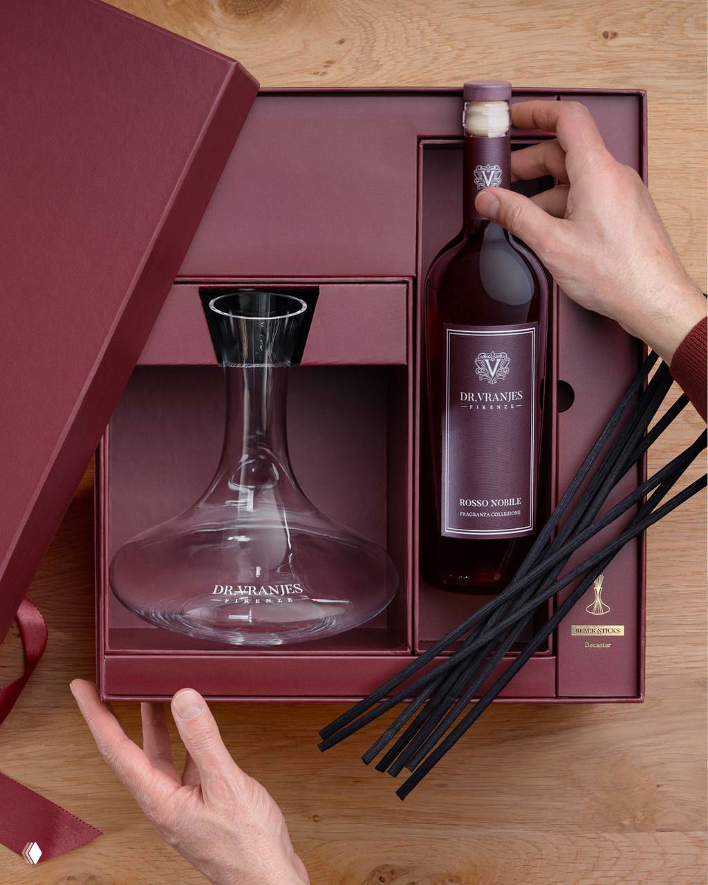 Подарочный набор Dr. Vranjes Firenze с бутылкой ароматической смеси и графином, руки упаковщика показывают оформление набора для подарка.