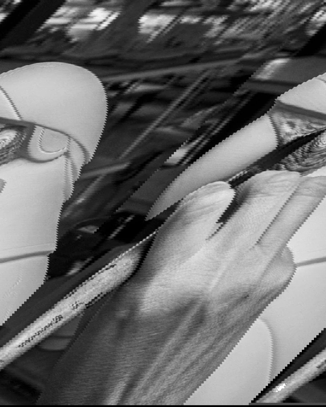 Ручная роспись головы попугая: мастер прорабатывает глаз и клюв кистью, чёрно‑белая фотография в мастерской.