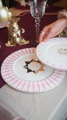 Крупный план розово‑золотой сервировки: тарелки Shirokov «Пурпур», прозрачные бокалы, золотая фигурка и пастельная скатерть в праздничном антураже.