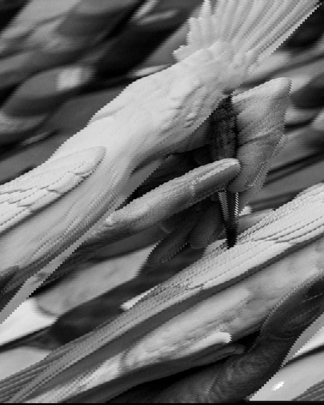 Процесс ручной росписи: кисть художника прорабатывает перья фарфоровой фигурки попугая, чёрно‑белая студийная съёмка.