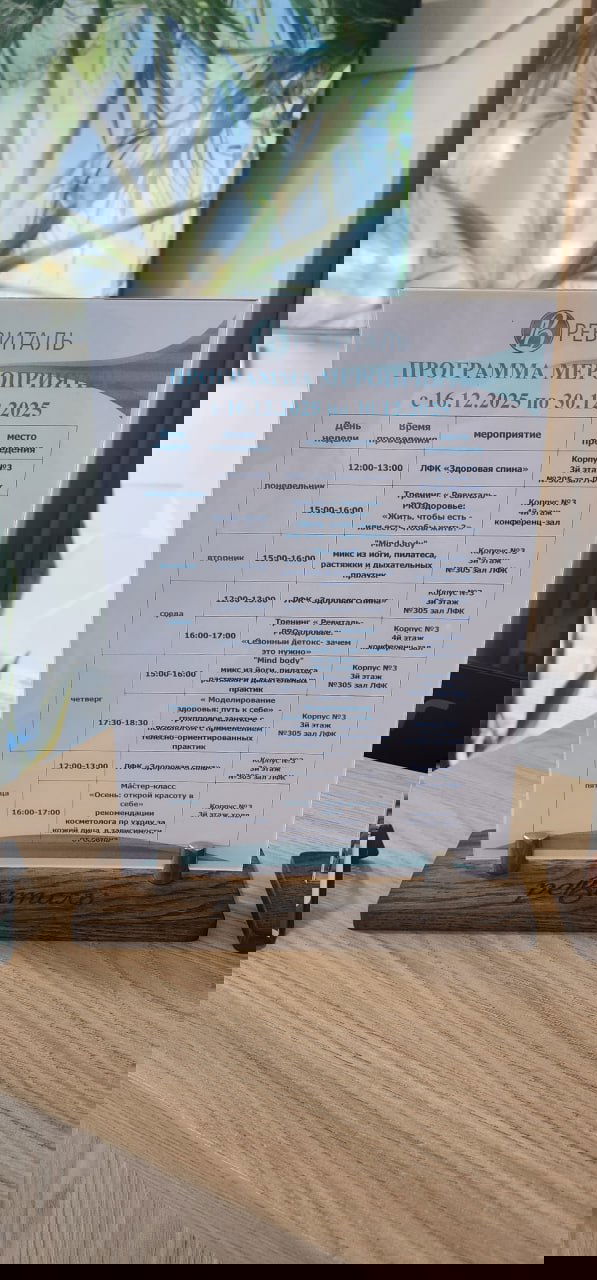 Печатная программа мероприятий санатория «Ревиталь» с расписанием процедур и оздоровительных занятий на стойке ресепшн, таблица с датами и временем.