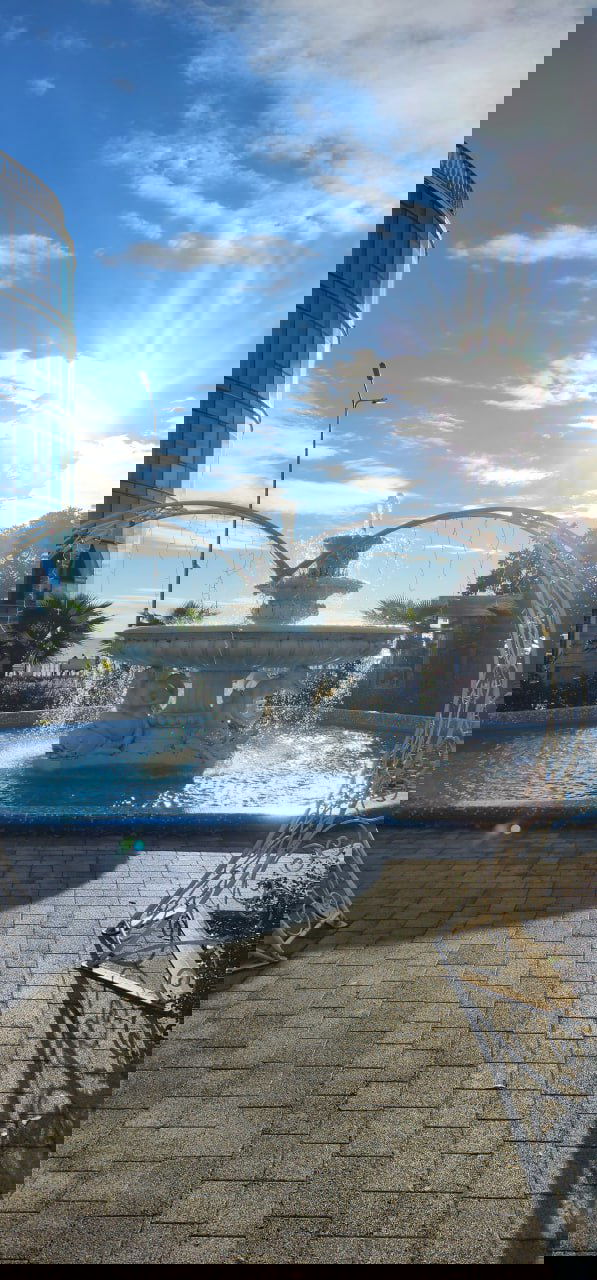 Утренний кадр с фонтаном на территории курорта в Сочи: солнце, брызги воды и архитектурные элементы на набережной рядом с корпусами.