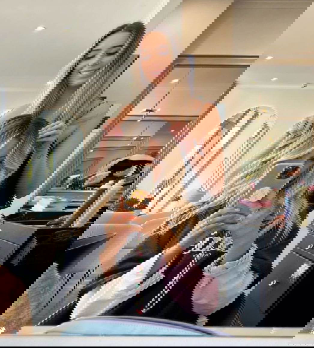 Клиентка в кресле салона делает селфи после укладки, мастер стоит за ней в интерьере салона — иллюстрация UGC и соцдоказательства для рекламы.