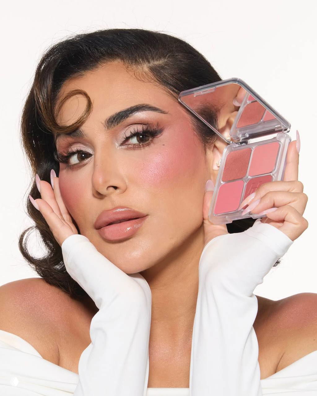 Рекламная фотография с крупным планом: лицо женщины в розовых тонах, демонстрирующей компактную палетку румян и блеск для губ, акцент на коже и декоративной косметике.