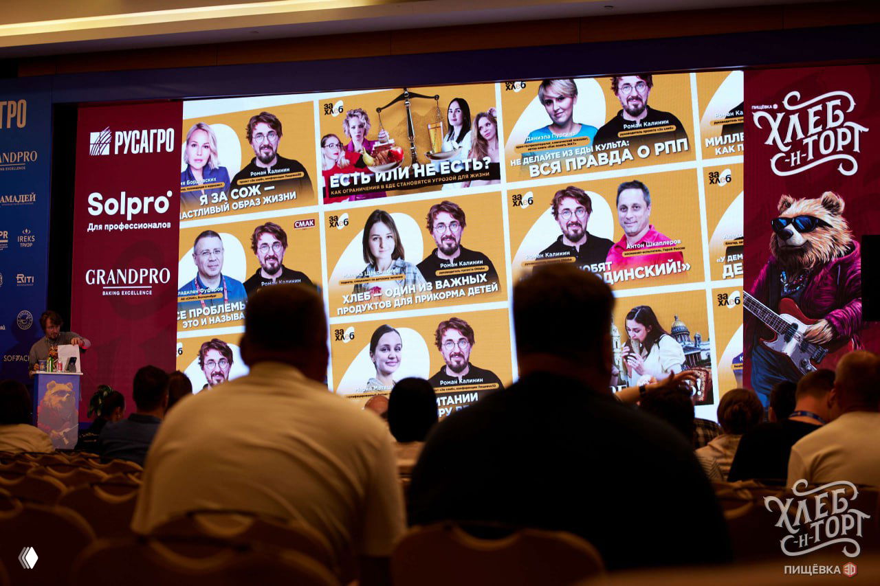 Аудитория на конференции ХЛЕБ-Н-ТОРТ смотрит на большой экран с плиткой изображений спикеров и визуалами проекта «За хлеб», вечерняя секция и зрители в креслах.