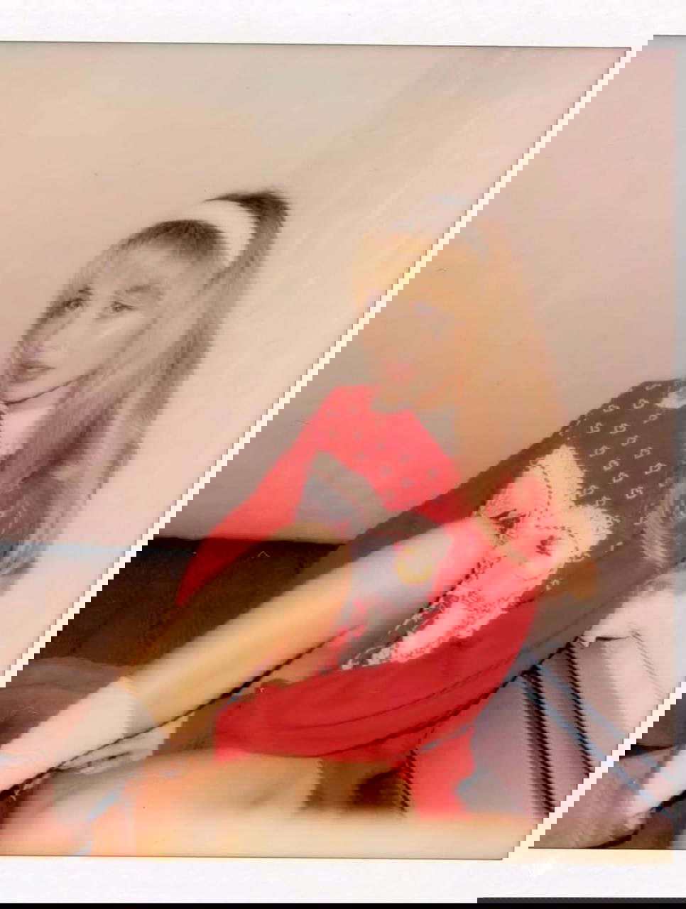 Портрет в полароидном стиле: женщина в красном свитере сидит на полу, мягкое освещение и ретро-эстетика кадра подчёркивают интимность снимка.