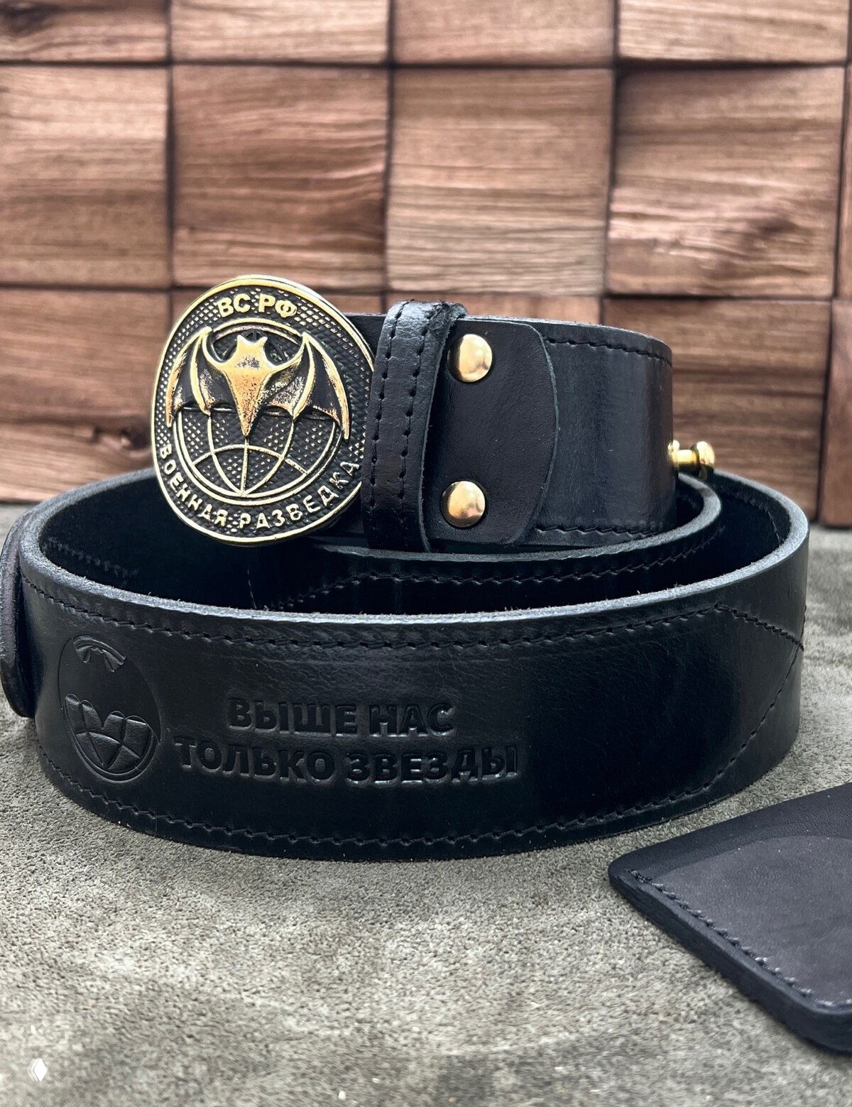 Чёрный широкий ремень с тиснением и круглой пряжкой с эмблемой военной разведки (внешняя съёмная пряжка), крупный план.