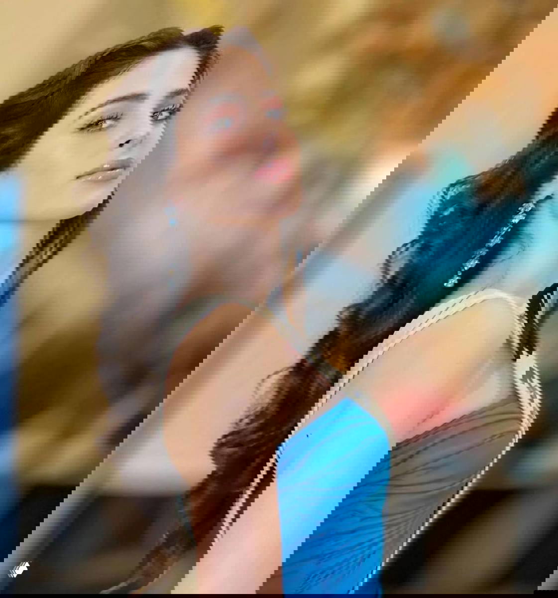 Крупный план женщины с длинными тёмными волосами, серьгами и нежным макияжем — портретный кадр с мероприятия, акцент на лице и украшениях.