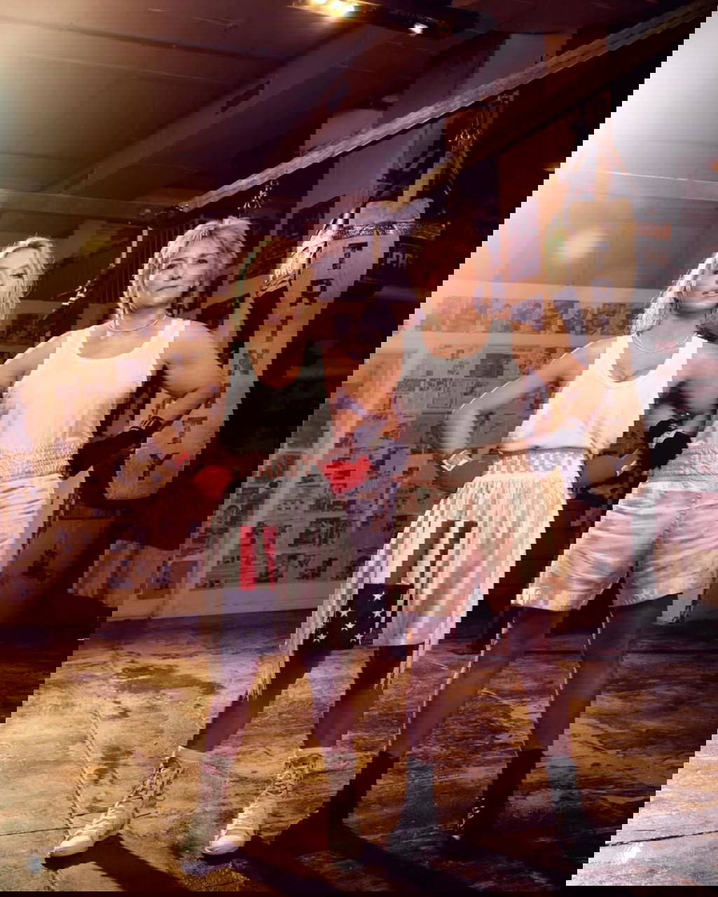 Сидни Суини и актриса, изображающая Кристи Мартин, позируют вместе в тренировочном зале рядом с боксерским мешком и газетными вырезками на стене.