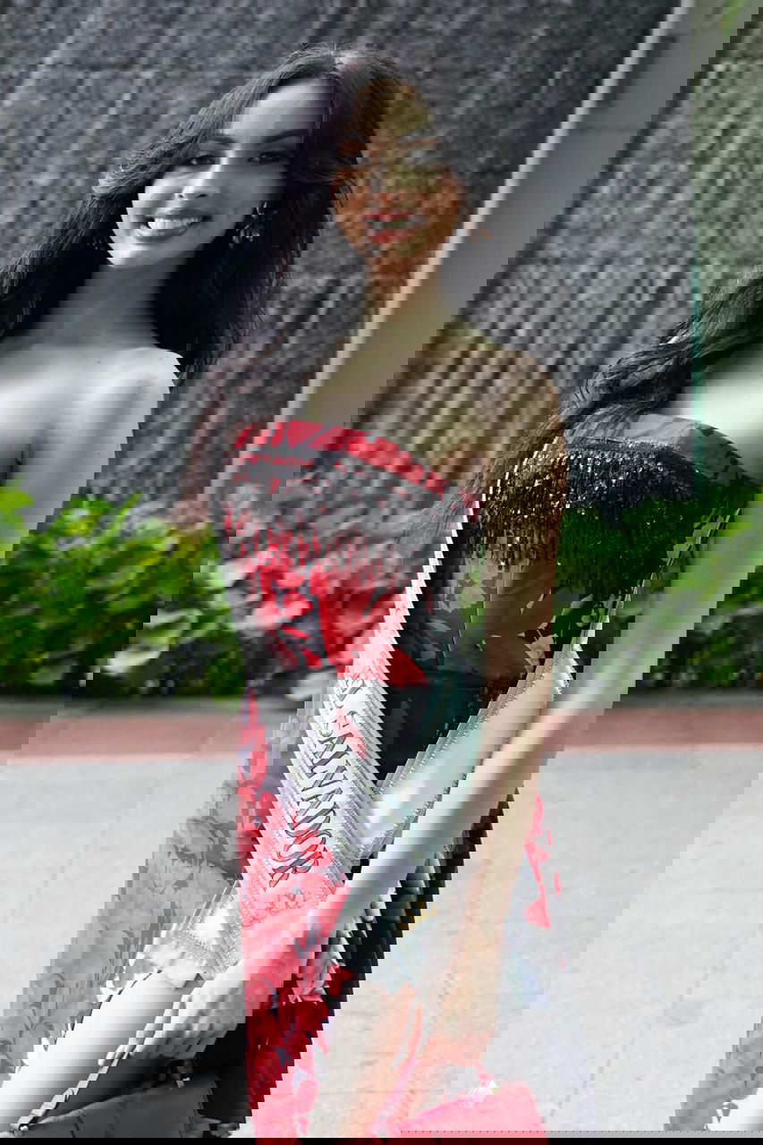 Участница конкурса с лентой «EL SALVADOR» в красном платье с цветочным принтом, портретная фотография на прогулке