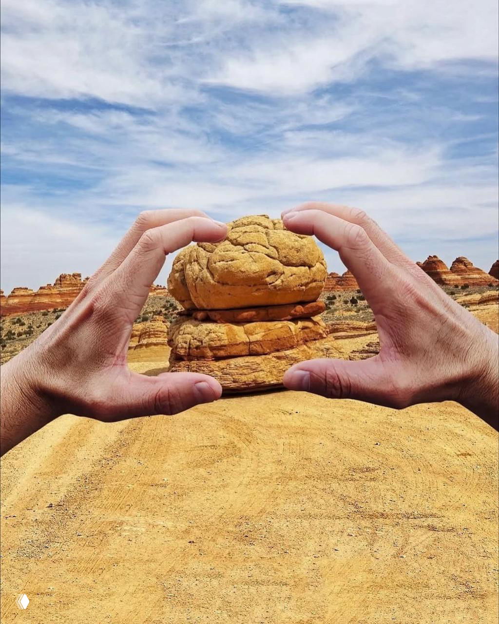 Две руки вблизи обрамляют необычную скалу, создавая оптическую иллюзию маленькой «бутербродной» скульптуры в пустынном пейзаже.