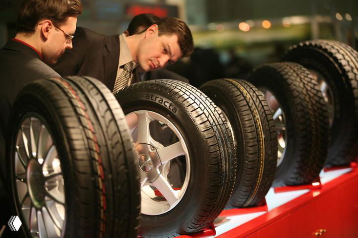 Ряд автомобильных шин разного протектора и ширины на витрине, наглядная иллюстрация выбора резины для экономии топлива