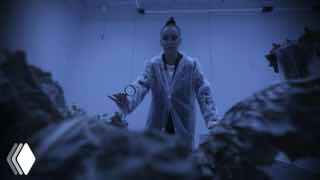 Кадр из третьего сезона: Ольга Бузова в рабочем халате среди растений и сельскохозяйственных помещений, сцена из проекта про аграрное образование.