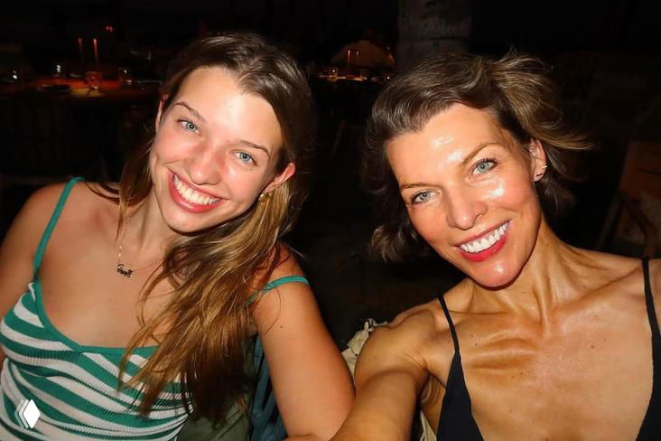 Дружеское фото двух женщин на вечеринке, искренние улыбки, тёплое освещение и непринуждённая атмосфера снимка.