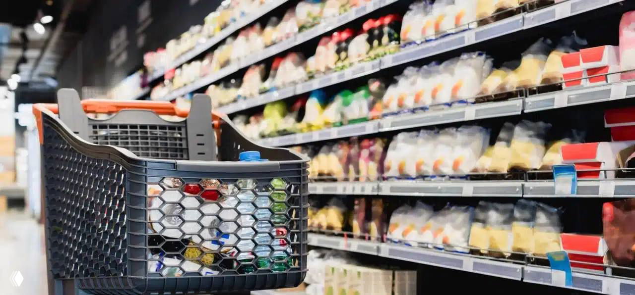 Покупательская корзина с упакованными продуктами на фоне полок супермаркета — иллюстрация категорий повседневных товаров и ритейла.