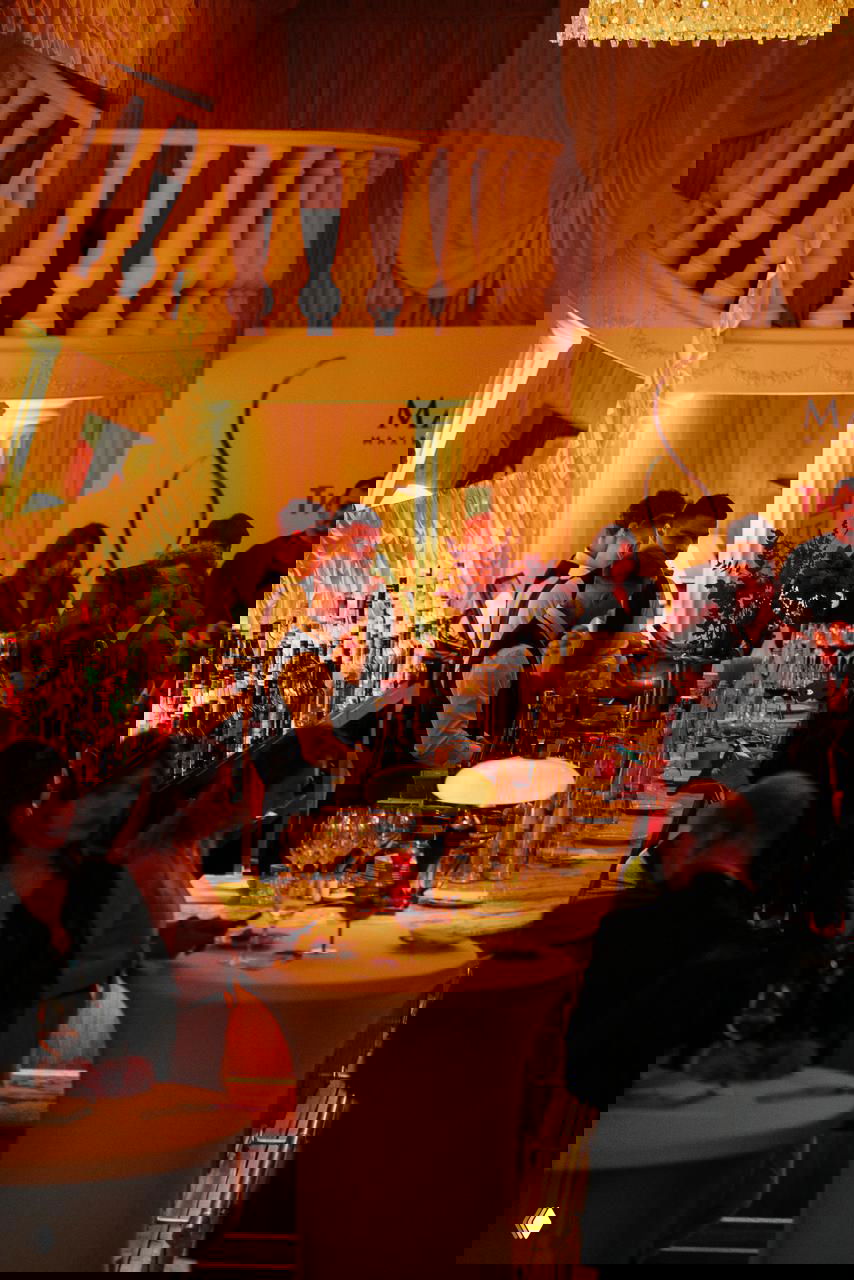 Бар и стойка с официантами в форменной одежде на мероприятии, кадр показывает интерьер зала с балюстрадой и гостями у бара