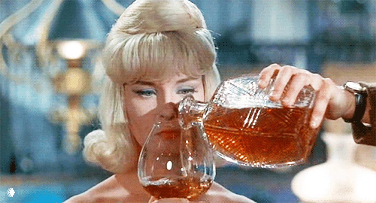 Кадр женщины, наливающей коньяк из графина в бокал: интерьерная сцена с акцентом на цвет напитка и атмосферу дегустации.