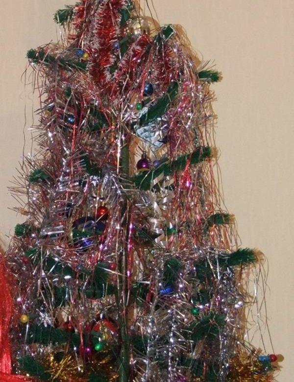 Ёлка, густо покрытая разноцветной мишурой и стеклянными шарами, немного асимметричная — пример любительского праздничного оформления.