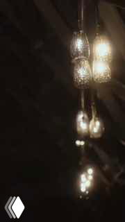 Вертикальный кадр — размытые подвесные светильники на тёмном фоне, атмосферный превью-кадр из видео с предложением руки и сердца.