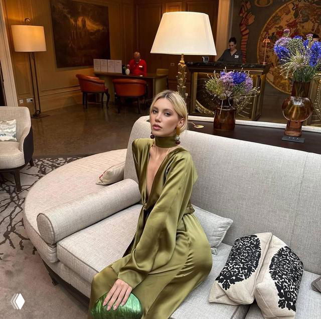 Натали Пушкинова в зелёном шелковом платье позирует на диване в отеле — фотосессия в рамках мероприятий Miss Earth 2025.