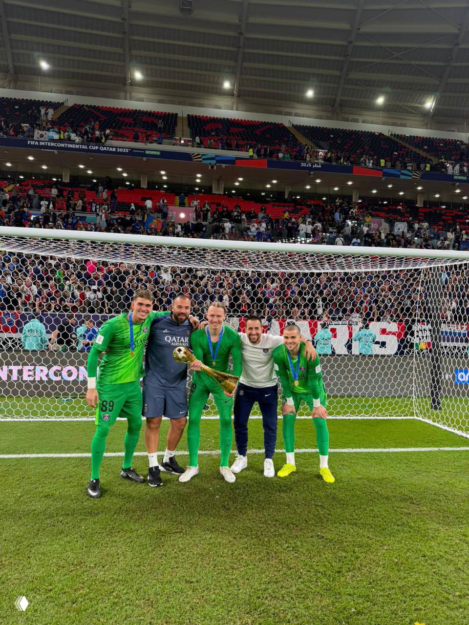 Игроки ПСЖ у ворот на поле позируют с трофеем Межконтинентального кубка после финала, в кадре видна трибуна.