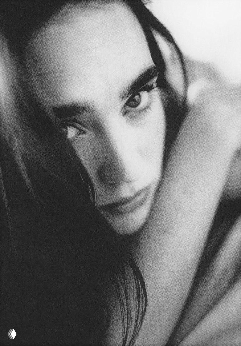 Крупный план лица молодой женщины в чёрно‑белой плёночной съёмке, выразительный взгляд, заметная зернистость и интимная атмосфера.