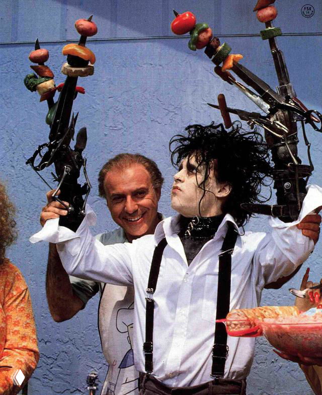 Колоритный фрагмент съёмок: персонаж с механизированными руками-ножницами держит реквизит на фоне декора и съёмочной группы.