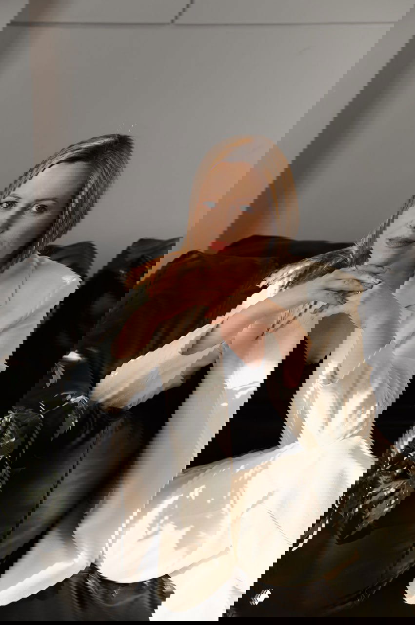 Портрет автора — адвокат Татьяна Кархалёва в светлом костюме, сидит на кожаном диване в офисной обстановке, деловой портрет для поста о франшизах.