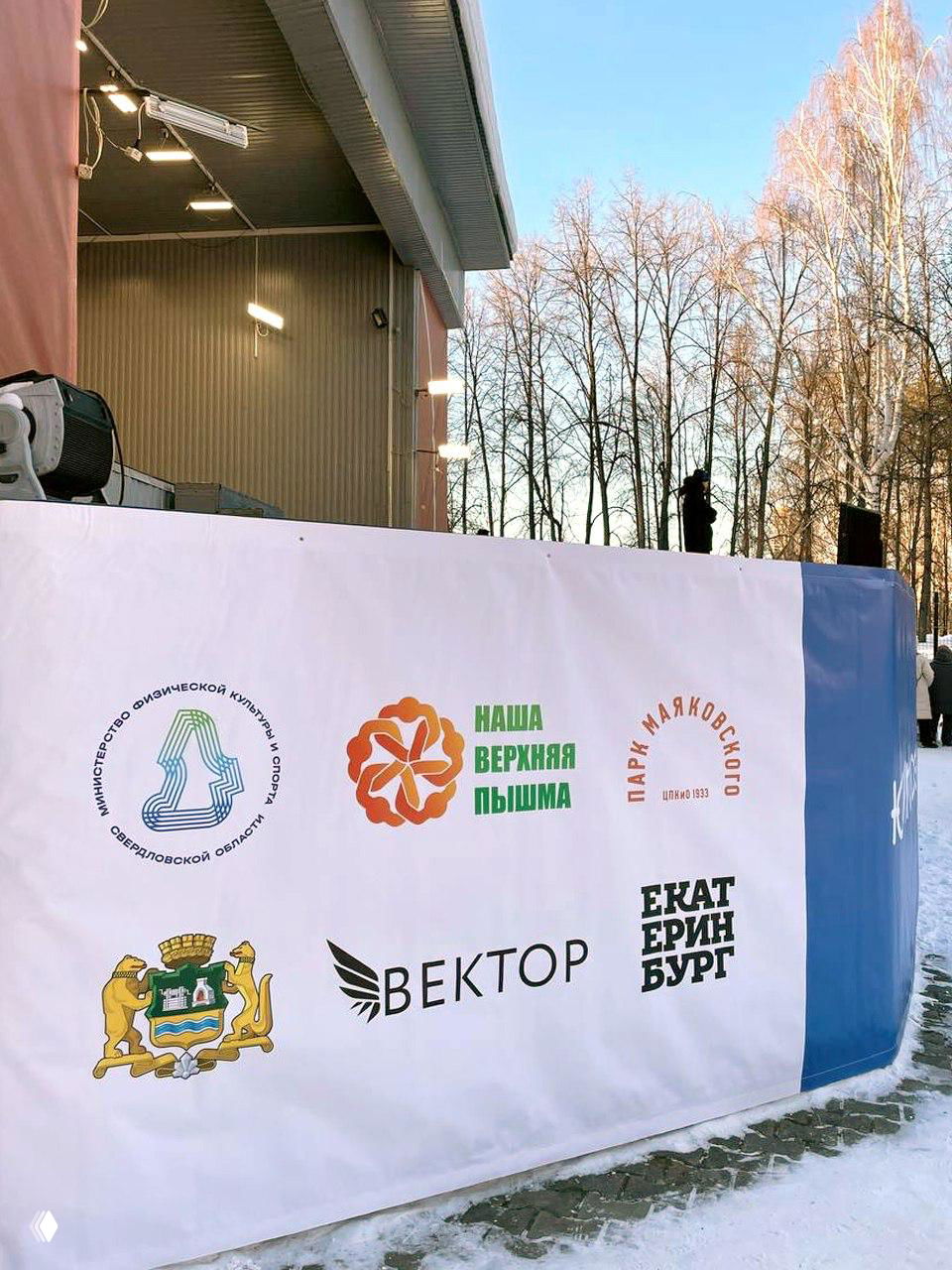 Большой баннер с логотипами проектов и гербом Екатеринбурга на зимнем мероприятии, видно несколько фирменных символов и названий организаторов.