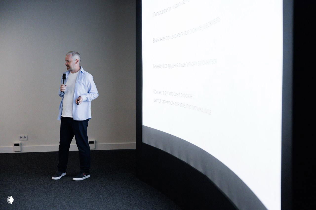 Мужчина с микрофоном ведёт презентацию у большого белого проекционного экрана — иллюстрация лекции по персональному бренду.