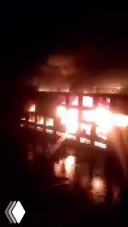 Ночной кадр горящего круизного лайнера на реке Нил: яркие языки пламени охватывают палубу, густой дым поднимается и отражается в воде.