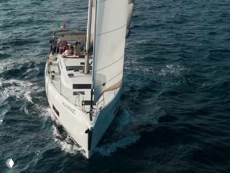 Вид на носовую часть яхты, идёт вперёд по морю; на корпусе виден регистрационный номер, подчёркивающий реальность судна в кадре.