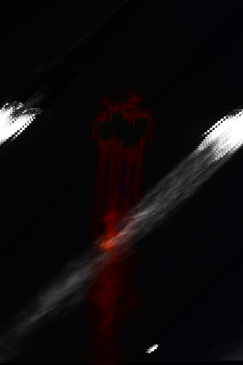 Крупный план работающих сопел ракеты «Союз»: интенсивное пламя и разноцветный газовый шлейф на тёмном небе во время набора скорости.