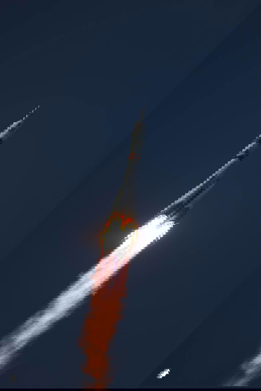 Ракета «Союз» в полёте после старта на фоне неба: яркий огненный след от двигателей и траектория подъёма вверх.