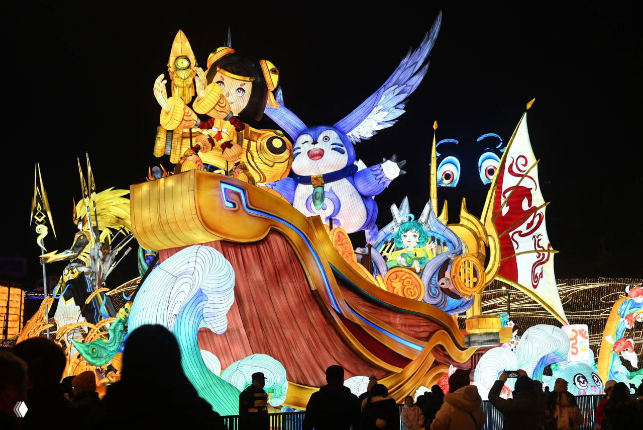 Зрители фотографируют крупную цветную инсталляцию с фантастическими персонажами и конями; ночная сцена фестиваля демонстрирует масштаб и детализацию работ.