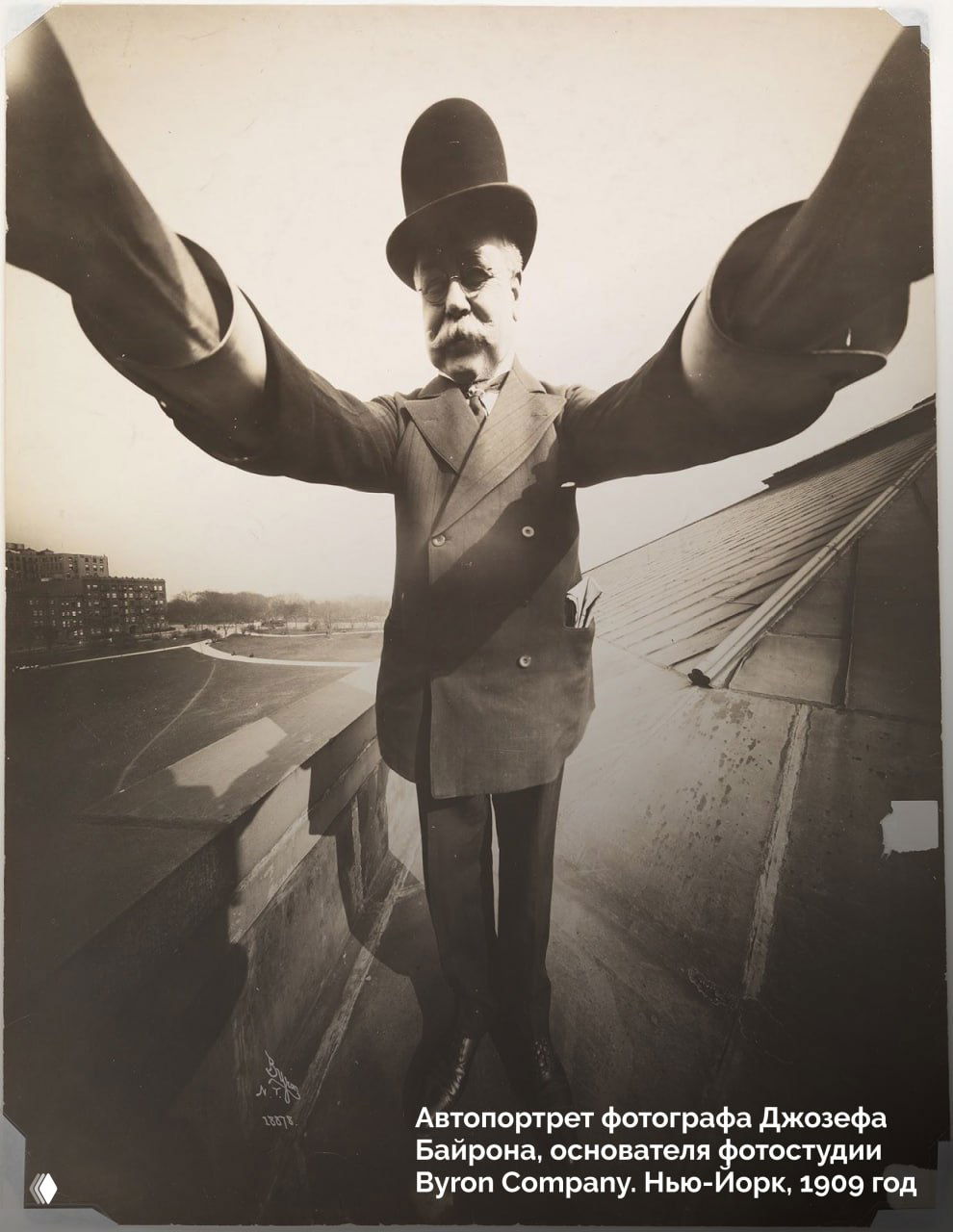 Автопортрет Джозефа Байрона, Нью‑Йорк, 1909: мужчина в цилиндре снимает себя с вытянутыми руками на крыше, виден городской пейзаж.