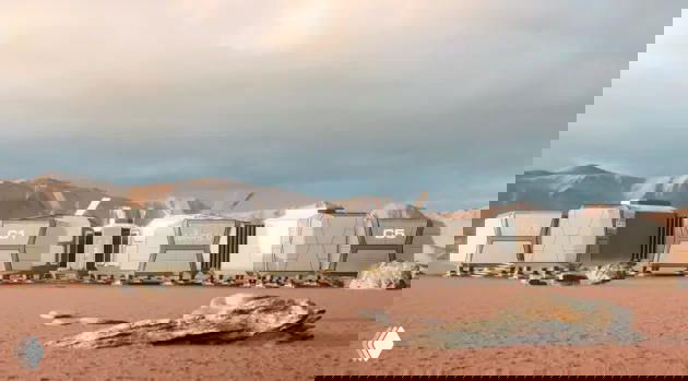 Панорамный кадр рядов капсульных модулей на пустынной равнине Гоби на фоне гор — концепт имитации марсианской базы для научно‑туристического проекта.