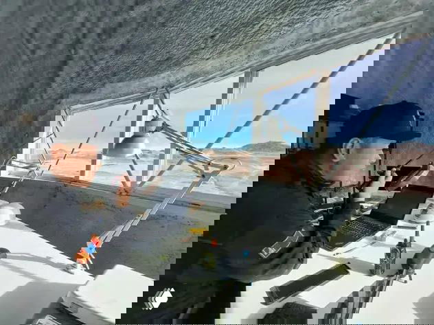 Интерьер модульной лаборатории: человек за рабочим столом с ноутбуком и приборами, через окно видна пустыня — рабочая зона внутри имитируемой станции.