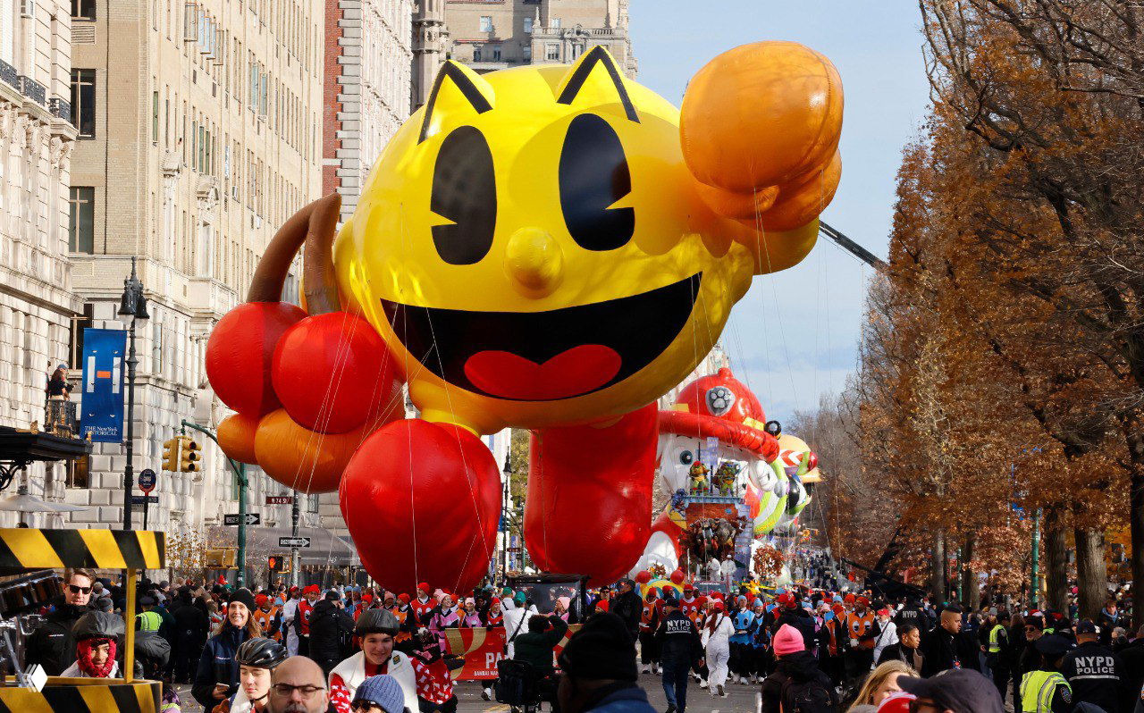 Большой желтый игровой персонаж Pac‑Man в виде надувного шара движется по Манхэттену во время парада, на тротуарах множество зрителей.