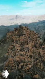 Аэрофото заброшенного аула Гамсутль в Дагестане: скопление каменных руин на вершине горы, террасы и разбросанные стены.