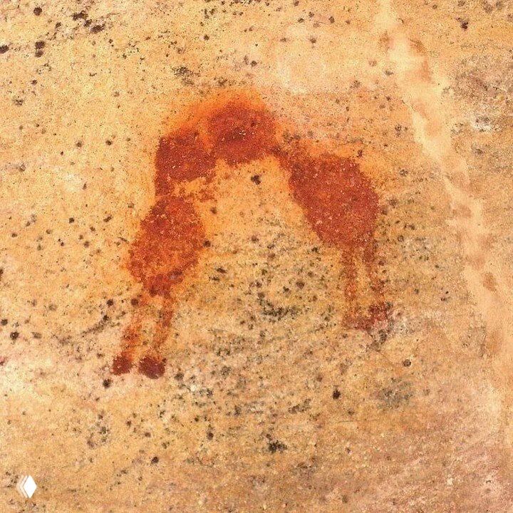 Фрагмент красного пятна на каменной поверхности, напоминающий схематичное наскальное изображение двух лиц, будто соприкасающихся губами