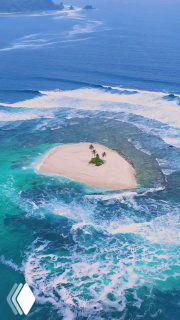 Аэрофотоснимок крошечного необитаемого островка архипелага Ментавай: песчаная коса, пара пальм и окружающие бирюзовые океанские воды.