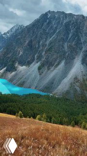 Вид на бирюзовое Шавлинское озеро в Алтае, окружённое крутыми каменными склонами Северо-Чуйского хребта на высоте около 2000 м.