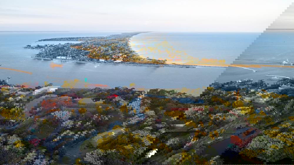 Аэрофотоснимок Балтийской косы и устья: песчаная коса, прибрежные леса, поселение и фортификационные строения на берегу Балтийского моря.