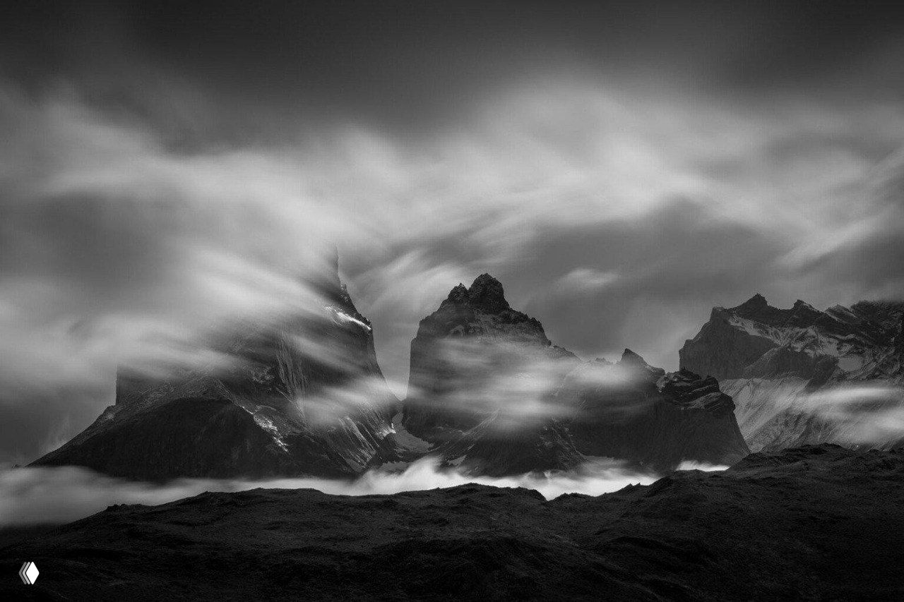 Черно‑белый панорамный пейзаж Патагонии с резкими скалами и стремительными облаками на фоне, драматическая фотография победителя конкурса.