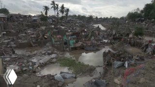 Разрушенные дома и затопленные улицы на Филиппинах после тайфуна «Калмаэги»: завалы, стоячая вода, пальмы и обломки под пасмурным небом.